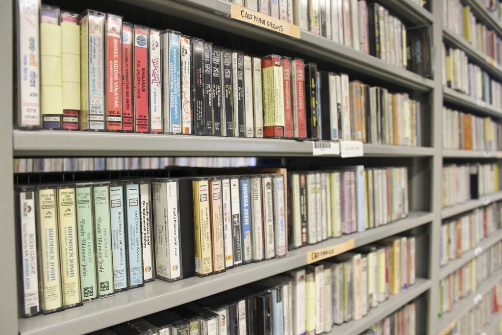 Library shelves lined with rows of audio cassette tapes in their cases.